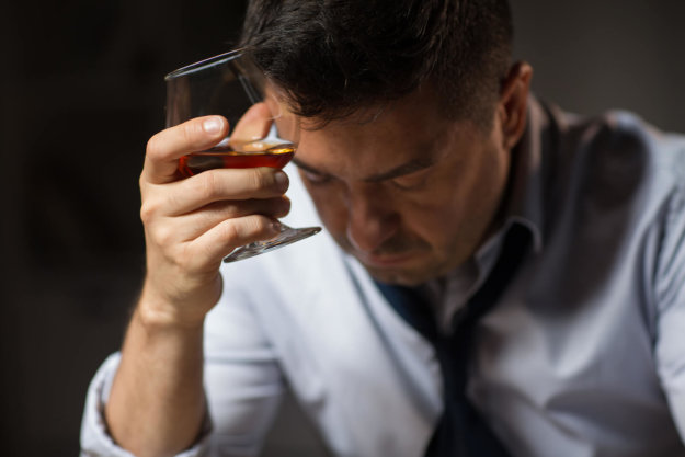 Why is Alcohol Addictive? Learn About the Leading Factors. A rundown businessman holding a glass of whiskey.
