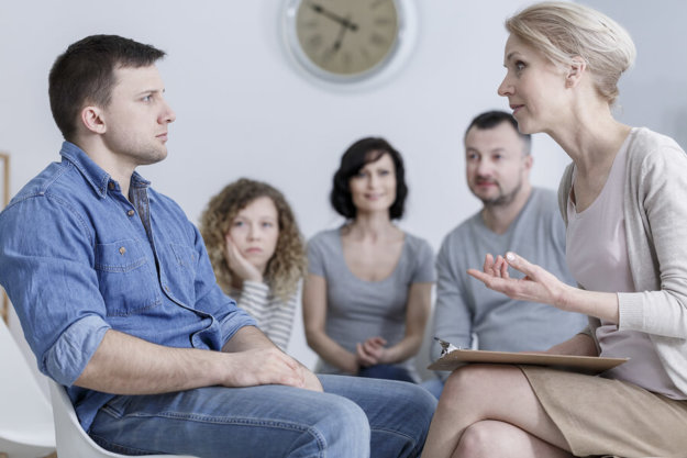 Why Choose Silver Maple Recovery for Drug Detox? A man struggling with substance abuse talking to an addiction professional with his family in the background.