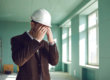 A stressed-out construction foreman covering his face with his hands.