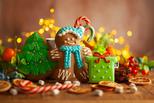 A picture of a gingerbread man in front of an assortment of Christmas desserts.