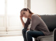 A woman in recovery sitting on a couch looking anxious and distressed.