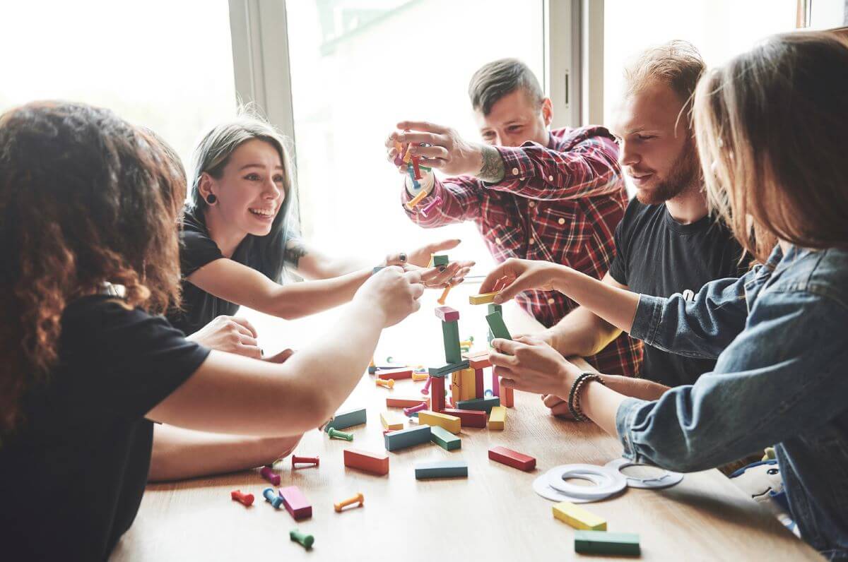 A group of friends sitting at a wooden table playing a board game.