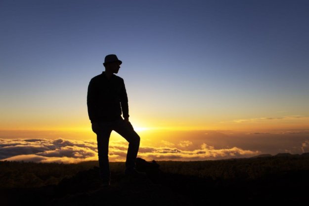 bigstock-Man-Leader-Stands-On-A-Mountai-331249312 A man standing on a mountain at sunset thinking about a higher power.