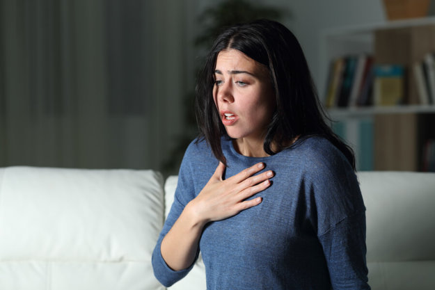 The Relationship Between Anxiety and Heroin A woman having a panic attack on her couch at home.