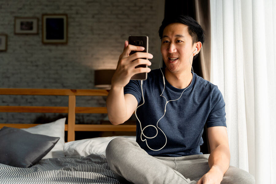 At-Home Alternatives for AA and SMART Recovery A man with headphones in, talking on a virtual AA meeting at home.