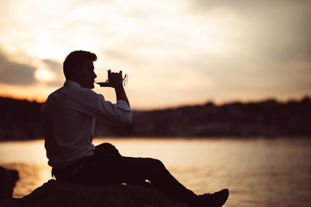 A man addicted to alcohol drinking outside.