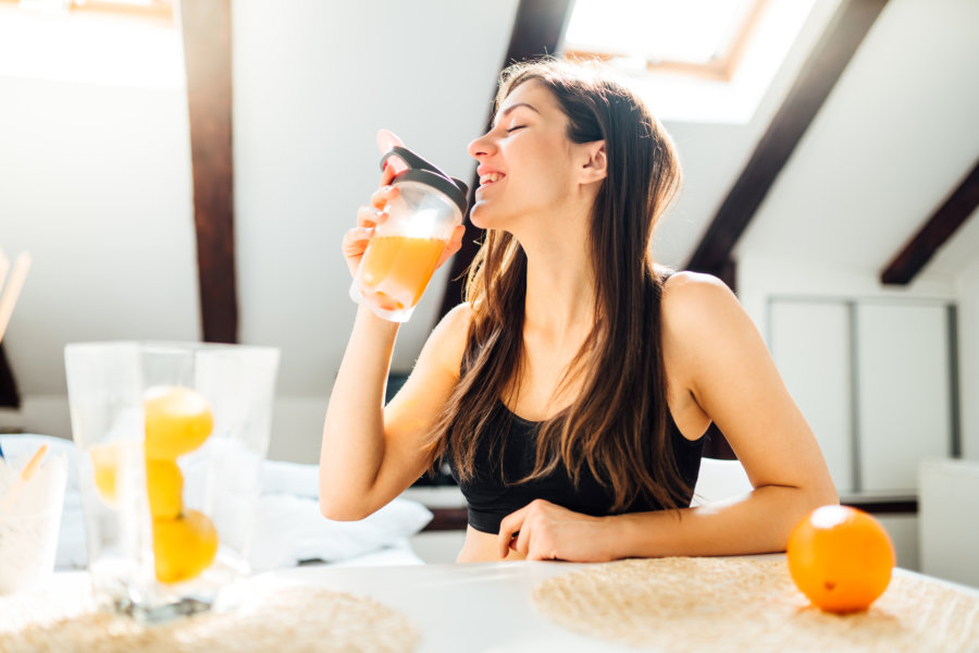 Woman At Home Drinking Orange Flavored Amino Acid Vitamin Powder A woman drinking a smoothie to boost her immune system.